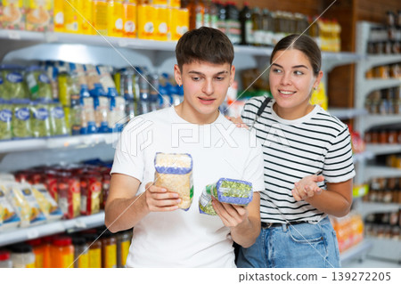 Young married couple carefully checks the information on product labels in hypermarket Young married couple carefully checks the information on product labels in hypermarket 139272205