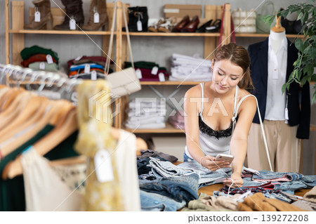 Young woman scanning qr code of pantalones in store Young woman scanning qr code of pantalones in store 139272208
