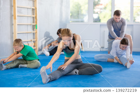 Parents with children family perform warm-up exercises and legs stretching Parents with children family perform warm-up exercises and legs stretching 139272219