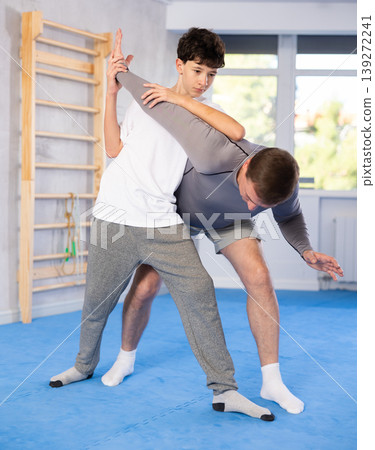 Father teaching his son wrestling or self-defense techniques in gym 139272241