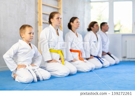 Team of family martial arts athletes is posing in gym with male coach. Team of family martial arts athletes is posing in gym with male coach. 139272261