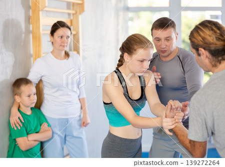 Trainer on man explains palm grab technique, boy, girl and woman watch and learn Trainer on man explains palm grab technique, boy, girl and woman watch and learn 139272264