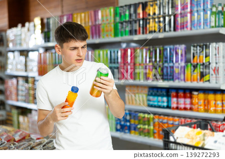Interested young guy choosing non-alcoholic beverages in supermarket Interested young guy choosing non-alcoholic beverages in supermarket 139272293