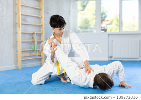 Teenage boy applying judo techniques on middle-aged trainer during sports classes Teenage boy applying judo techniques on middle-aged trainer during sports classes 139272310