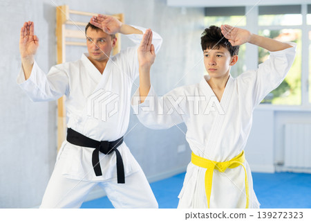 Individual karate lesson for teenager - fighting position of teenager and coach during karate training in gym Individual karate lesson for teenager - fighting position of teenager and coach during karate training in gym 139272323