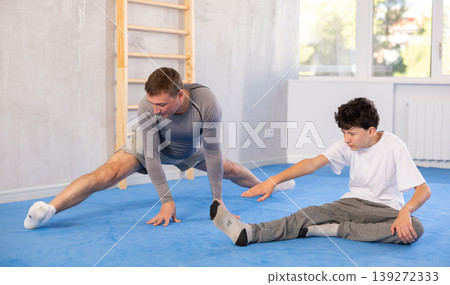 Man and boy teenager doing stretching exercises Man and boy teenager doing stretching exercises 139272333