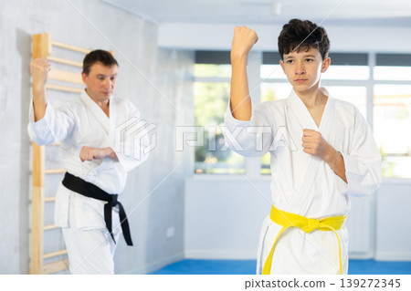 Karate trainer teaching block and punches to teenager in the gym 139272345