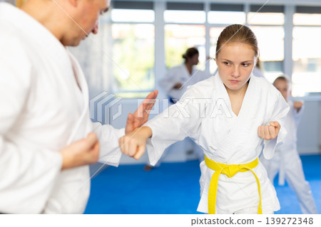 Teen girl is paired with male teacher to learn how to strike and rehearses blocking opponent Teen girl is paired with male teacher to learn how to strike and rehearses blocking opponent 139272348