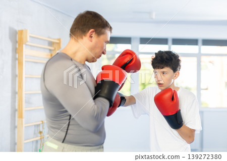 Father teaches son to box during individual boxing training in gym Father teaches son to box during individual boxing training in gym 139272380