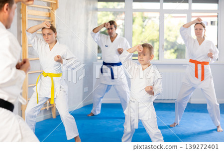Kid boy and his family repeat movements and learn fighting techniques during martial arts lesson 139272401