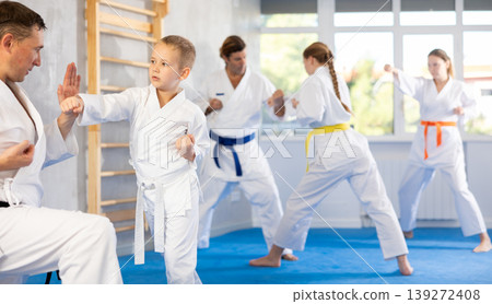 Boy is paired with man teacher to learn how to strike and rehearses blocking opponent Boy is paired with man teacher to learn how to strike and rehearses blocking opponent 139272408