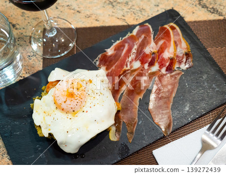 Slices of dark aged jamon complement stewed spring vegetables and scrambled eggs Slices of dark aged jamon complement stewed spring vegetables and scrambled eggs 139272439