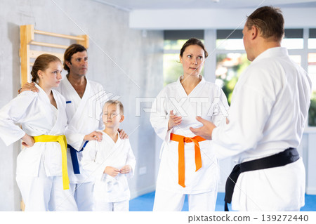 After completing family session and karate training, parents talk with male coach. 139272440