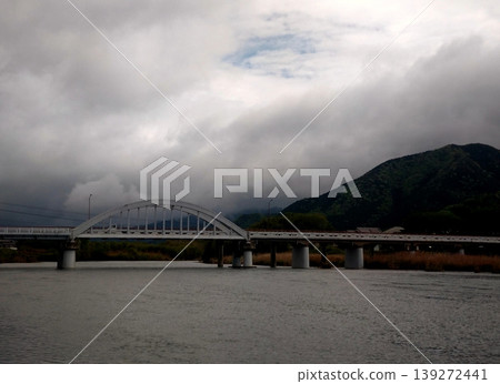 An arch bridge and a tranquil river under a cloudy sky. An arch bridge and a tranquil river under a cloudy sky. 139272441