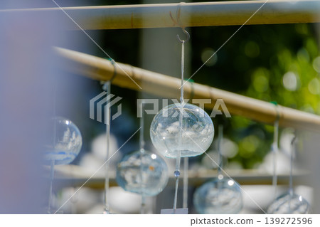 The transparent glass wind chimes sparkling in the sunlight and the coolness of summer The transparent glass wind chimes sparkling in the sunlight and the coolness of summer 139272596
