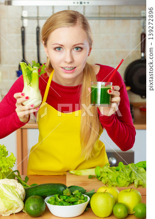 Woman in kitchen holding vegetable fennel smoothie juice Woman in kitchen holding vegetable fennel smoothie juice 139272896