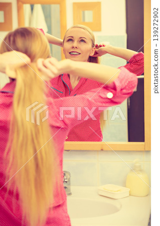Woman combing her long hair in bathroom Woman combing her long hair in bathroom 139272902