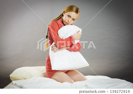Sad depressed girl in bed gripping pillow Sad depressed girl in bed gripping pillow 139272919