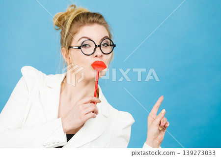 woman holds fake lips on stick pointing at copy space 139273033