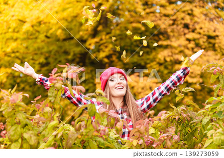 woman in autumn park throwing leaves up in the air woman in autumn park throwing leaves up in the air 139273059