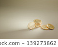 一枚在米色背景上閃耀著金光的硬幣。 139273862