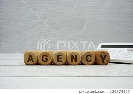 AGENCY alphabet letters with calculator on wooden background AGENCY alphabet letters with calculator on wooden background 139274195