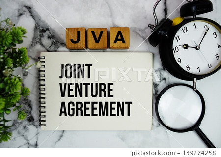 JVA Joint Venture Agreement text with alarm clock and magnifying glass on marble background JVA Joint Venture Agreement text with alarm clock and magnifying glass on marble background 139274258