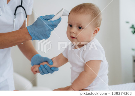 Temperature of body measurement. Female doctor is taking care of little baby girl in the clinic Temperature of body measurement. Female doctor is taking care of little baby girl in the clinic 139274363