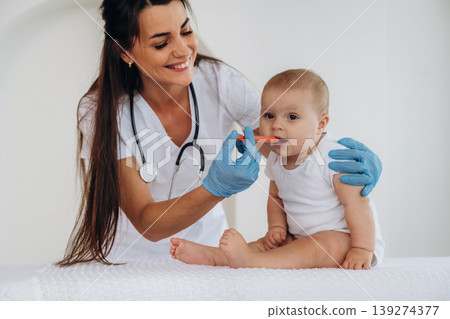 Giving medicine in syringe. Female doctor is taking care of little baby girl in the clinic 139274377
