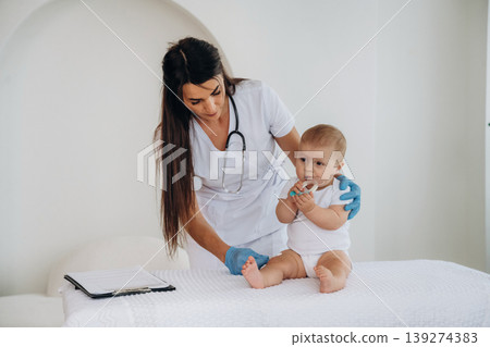 In the clinic. Female doctor is taking care of little baby girl In the clinic. Female doctor is taking care of little baby girl 139274383