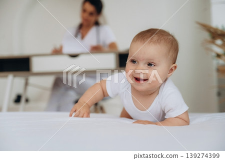 Resting on the white surface. Female doctor is taking care of little baby girl in the clinic Resting on the white surface. Female doctor is taking care of little baby girl in the clinic 139274399