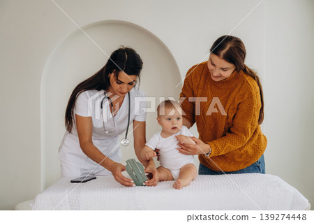 Board game, game for developing motor skills. Mother with her little baby daughter is in clinic with doctor at appointment Board game, game for developing motor skills. Mother with her little baby daughter is in clinic with doctor at appointment 139274448
