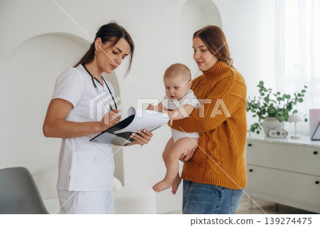 Consultation time. Mother with her little baby daughter is in clinic with doctor at appointment Consultation time. Mother with her little baby daughter is in clinic with doctor at appointment 139274475
