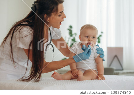 Kid is on the table. Female doctor is taking care of little baby girl in the clinic Kid is on the table. Female doctor is taking care of little baby girl in the clinic 139274540