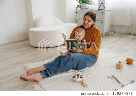 Reading a book. Happy mother with her baby daughter are at home together Reading a book. Happy mother with her baby daughter are at home together 139274578