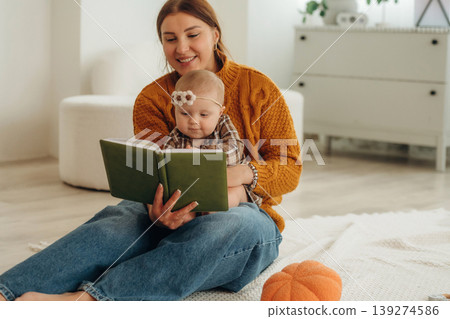 Interesting story reading. Happy mother with her baby daughter are at home together Interesting story reading. Happy mother with her baby daughter are at home together 139274586