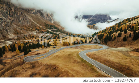 Twisted snake-like asphalt road. Pass near Cortina mountain. Aerial majestic view of popular place at autumn season, background Twisted snake-like asphalt road. Pass near Cortina mountain. Aerial majestic view of popular place at autumn season, background 139274767