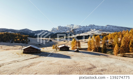 Wooden houses are on the land. Alpe di Siusi, Seiser Alm, aerial view of majestic dolomites, mountains background Wooden houses are on the land. Alpe di Siusi, Seiser Alm, aerial view of majestic dolomites, mountains background 139274775