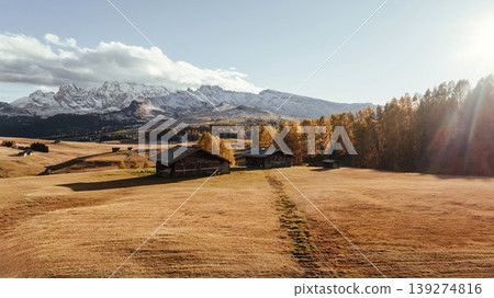 Field with wooden houses. Alpe di Siusi, Seiser Alm, aerial view of majestic dolomites, mountains background Field with wooden houses. Alpe di Siusi, Seiser Alm, aerial view of majestic dolomites, mountains background 139274816