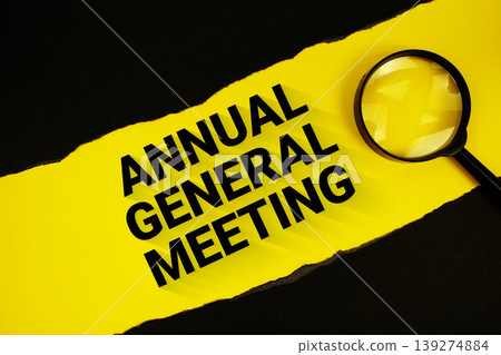 Annual General Meeting text on yellow with black paper torn ripped and magnifying glass Annual General Meeting text on yellow with black paper torn ripped and magnifying glass 139274884