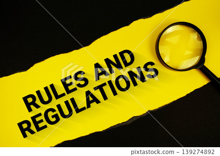 Rules And Regulations text on yellow with black paper torn ripped and magnifying glass Rules And Regulations text on yellow with black paper torn ripped and magnifying glass 139274892