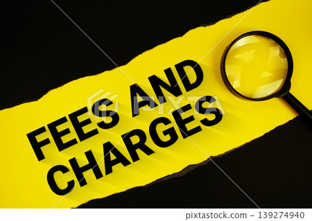 Fees And Charges text on yellow with black paper torn ripped and magnifying glass Fees And Charges text on yellow with black paper torn ripped and magnifying glass 139274940
