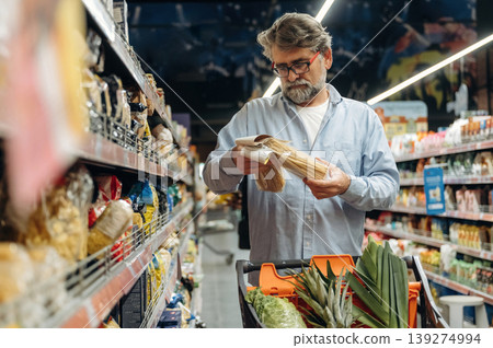 Choosing spaghetti, pasta. A senior man is buying food in the grocery store Choosing spaghetti, pasta. A senior man is buying food in the grocery store 139274994