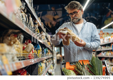 Choosing spaghetti, pasta. A senior man is buying food in the grocery store Choosing spaghetti, pasta. A senior man is buying food in the grocery store 139274995