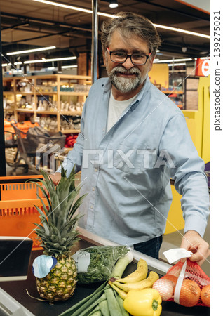 Standing at the checkout. A senior man is buying food in the grocery store 139275021