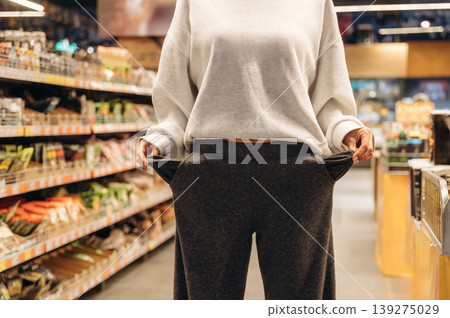 Woman is standing in grocery store with empty pockets, no money, poor Woman is standing in grocery store with empty pockets, no money, poor 139275029