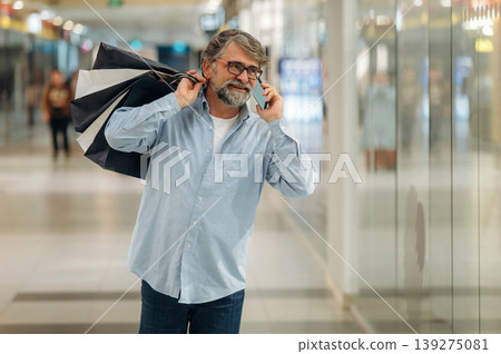 Making a call, talking. Senior man is in the mall, shopping time conception Making a call, talking. Senior man is in the mall, shopping time conception 139275081