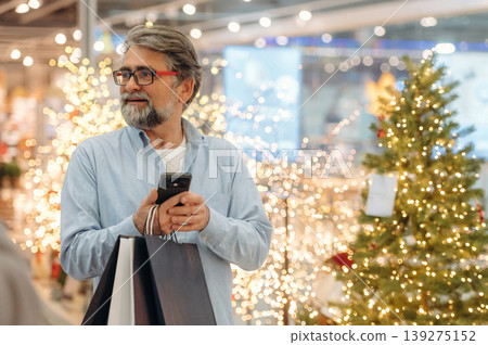New year decorations behind. Senior man is in the mall, shopping time conception New year decorations behind. Senior man is in the mall, shopping time conception 139275152