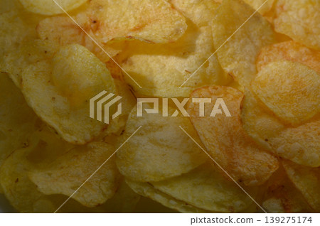 Crunchy potato chips glisten with golden hues in a close-up view showcasing their delightful texture and flavor Crunchy potato chips glisten with golden hues in a close-up view showcasing their delightful texture and flavor 139275174