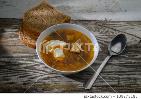 Comforting bowl of flavorful soup paired with fresh bread on rustic wooden table Comforting bowl of flavorful soup paired with fresh bread on rustic wooden table 139275183